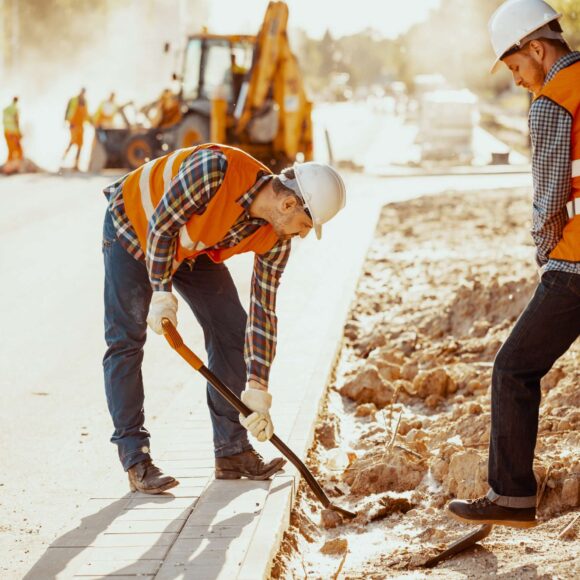 Workers in reflective vests using shovels during carriageway work